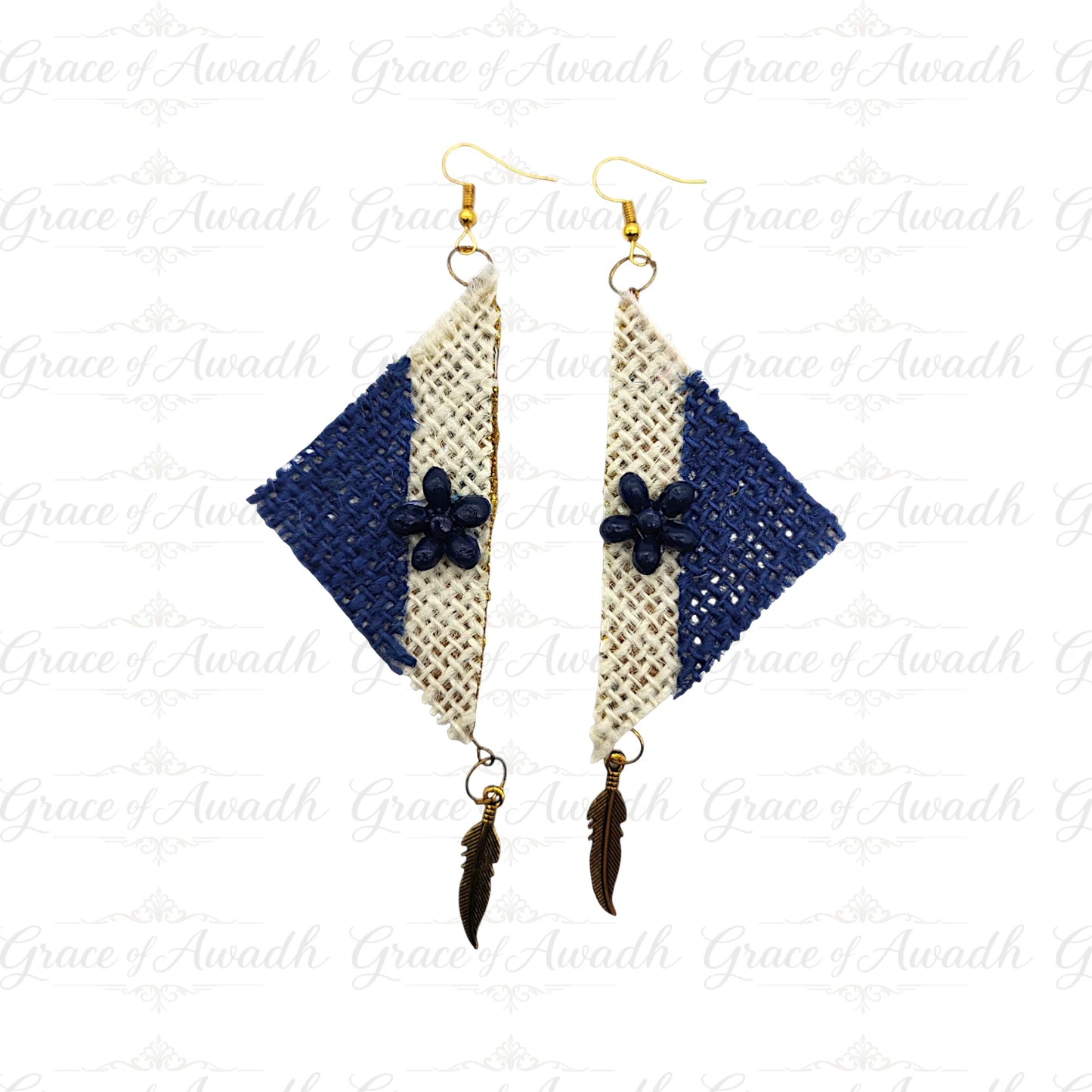 Pair of earrings with blue and beige diamond-shaped designs on a white background. Neel-e-Noor handcrafted blue and ivory fabric earrings with floral motif and feather charms – Grace of Awadh