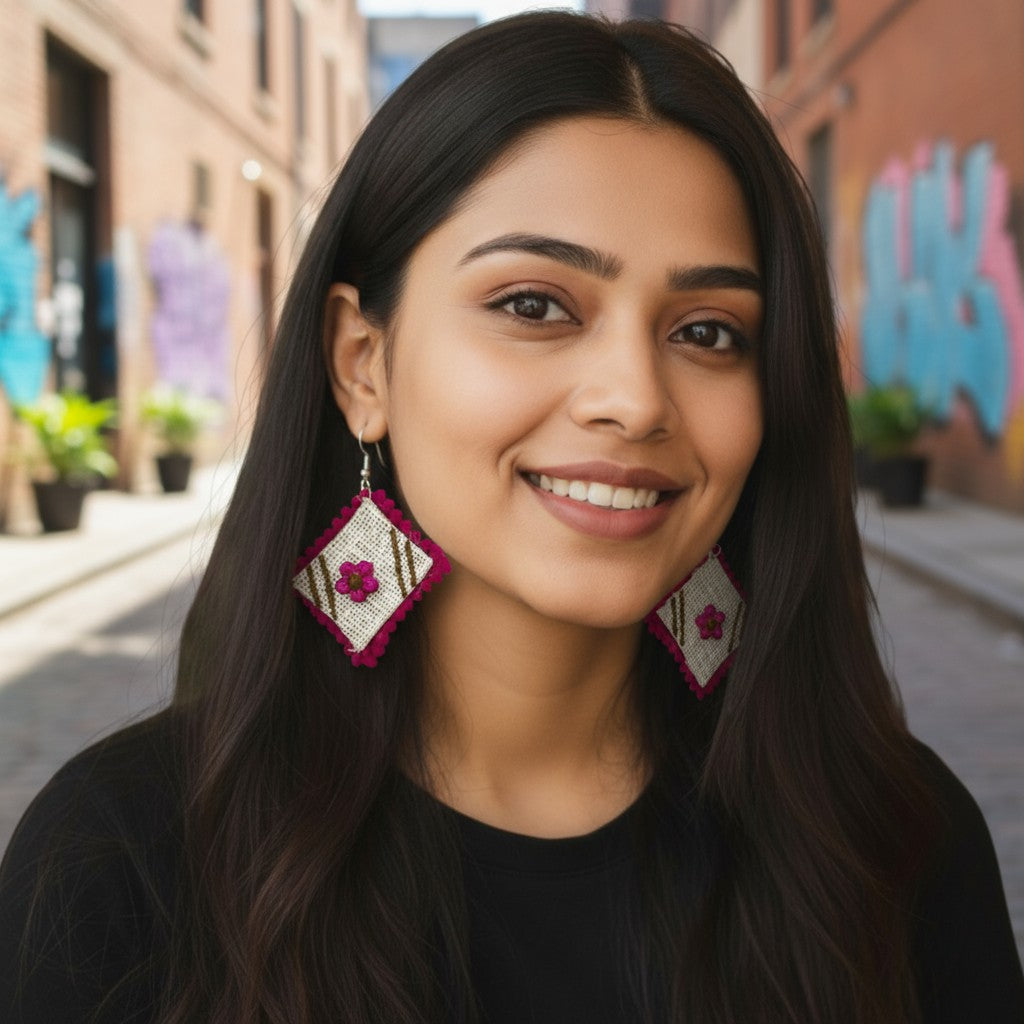 Woman wearing traditional earrings with a blurred street background Phool-e-Nazakat white fabric earrings with pink floral appliqué and fuchsia border – Grace of Awadh