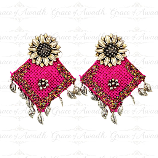 Pair of pink earrings with gold sunflower designs on a white ,
Rangrez-e-Jashn pink glitter sunflower earrings with silver leaf drops – Grace of Awadh