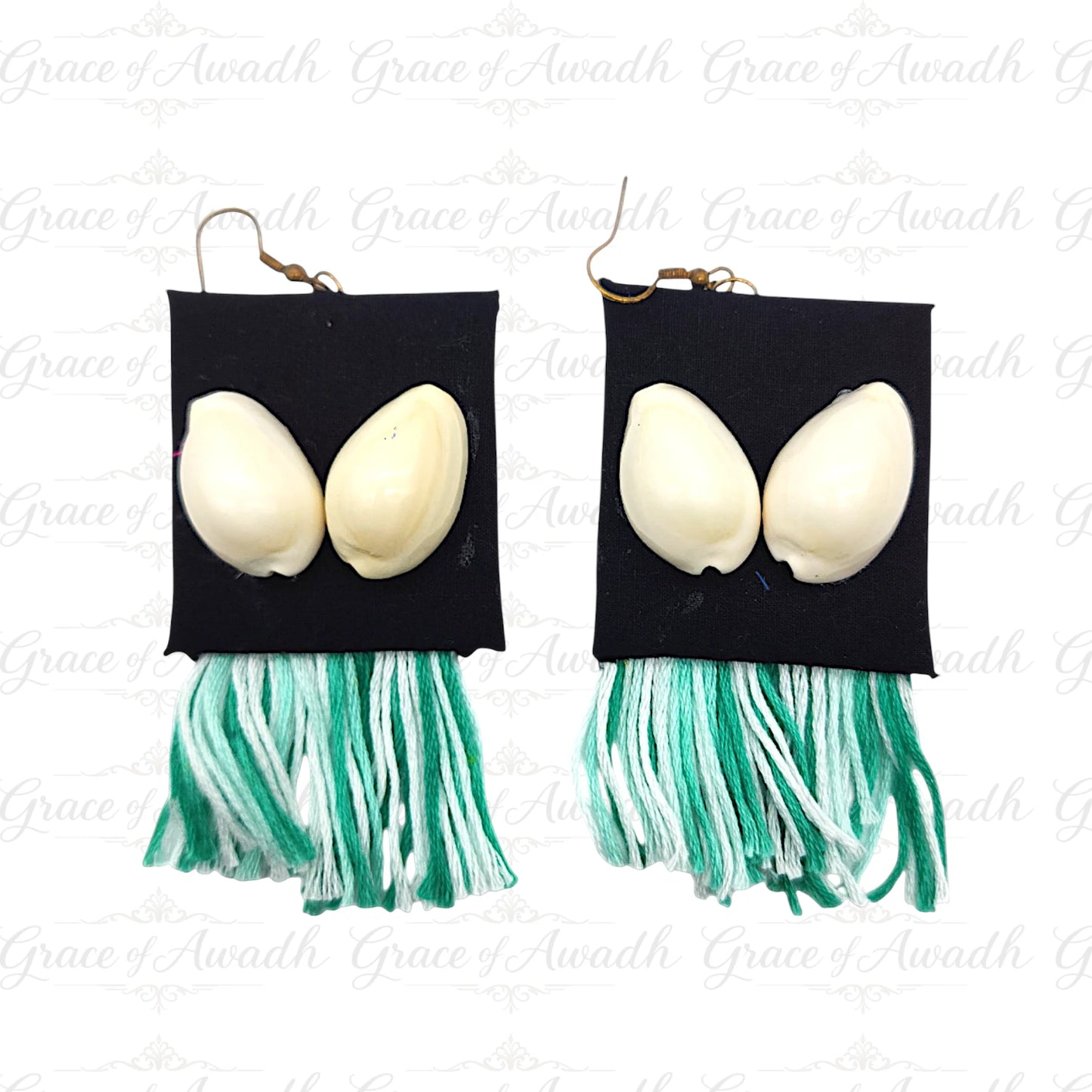 Pair of earrings with black square pendants, white eggs, and green tassels on a white background. Gehna-e-Samundar black base cowrie shell earrings with green tassels – Grace of Awadh