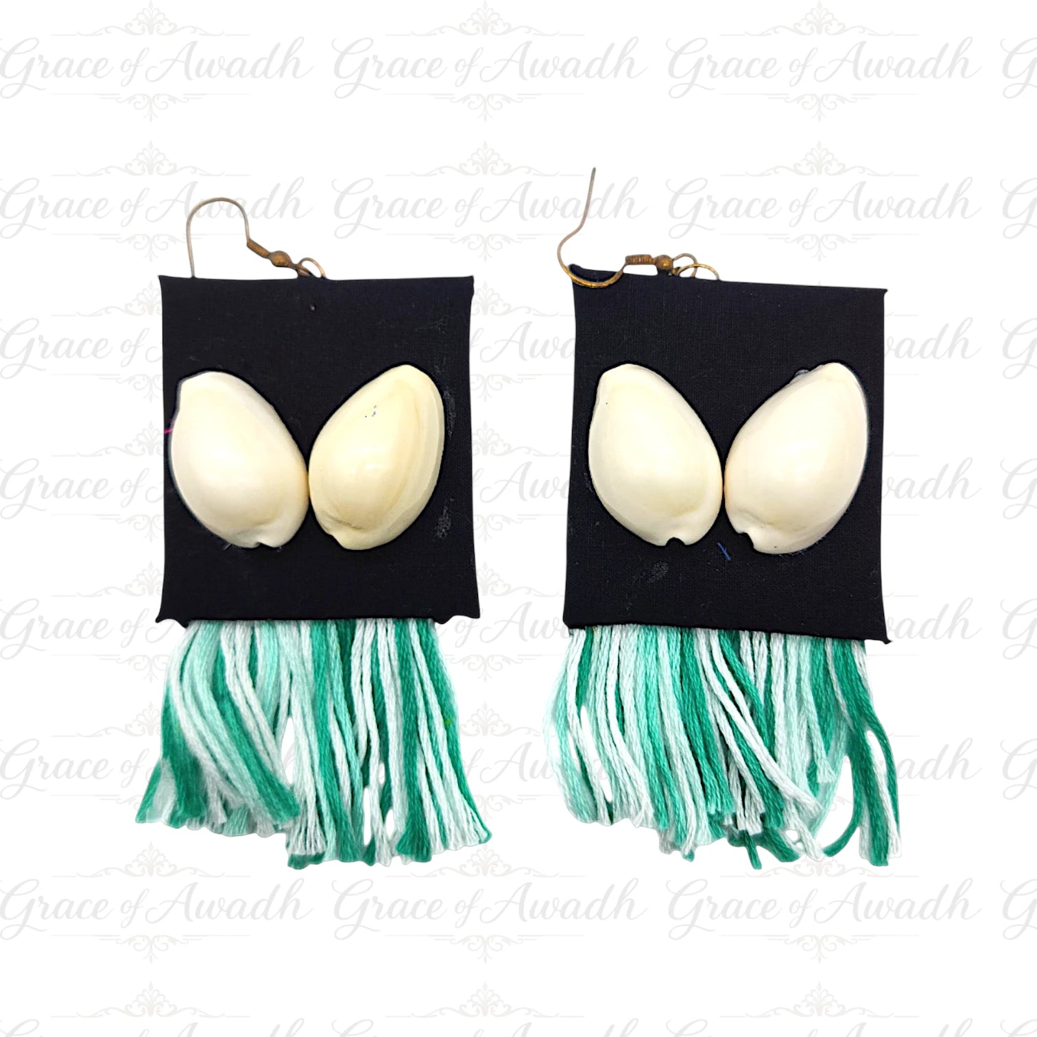Pair of earrings with black square pendants, white eggs, and green tassels on a white background. Gehna-e-Samundar black base cowrie shell earrings with green tassels – Grace of Awadh