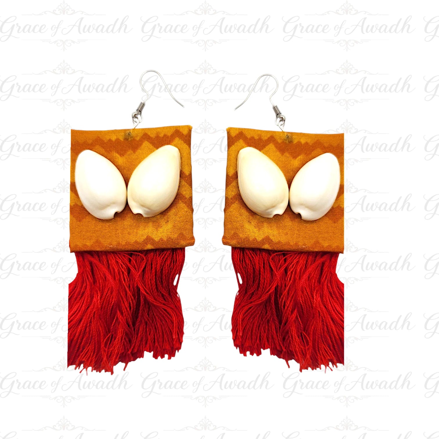 Pair of earrings with white eggs on orange square pads and red fringe on a white background. Gehna-e-Samundar mustard/orange fabric cowrie shell earrings with red tassels – Grace of Awadh